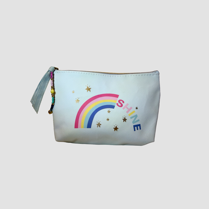A white cosmetic pouch featuring a colorful rainbow graphic, gold stars, and the word 'SHINE' in blue and pink, with a light blue tassel zipper pull on a neutral gray background.